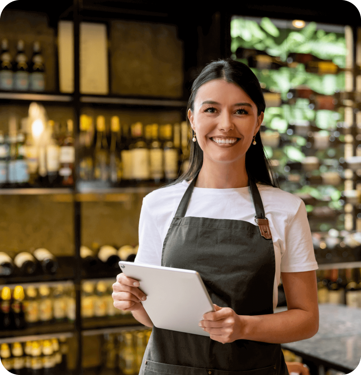 Smiling woman in apron holding tablet.