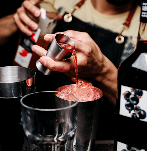 Bartender pouring cocktail into a shaker.